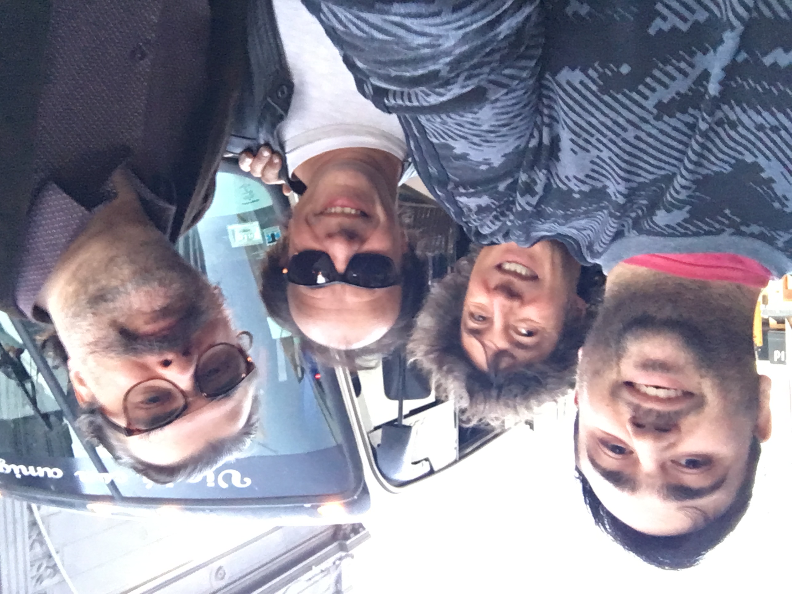 Three band members from "El Cuarteto de Nos" and me, standing close together and smiling for a selfie on the street, with a large tour bus in the background.